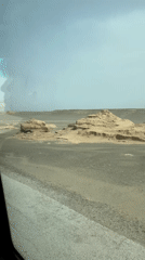 Vehicle travels desert road near Dunhuang City, China