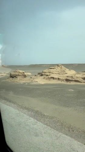 Vehicle travels desert road near Dunhuang City, China