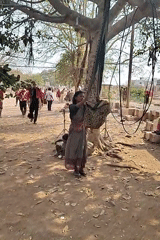 Woman hangs basket from tree as marching band passes
