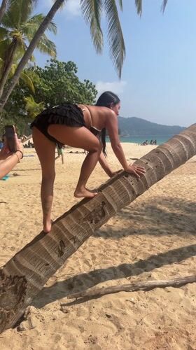 Woman climbs palm tree, performs ballet on Thai beach