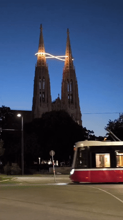 Vienna tram passes illuminated Gothic cathedral at dusk