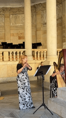 Flute and harp duo performing outdoors among stone columns
