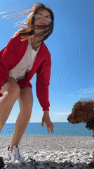 Woman plays with brown dog on Montenegro beach
