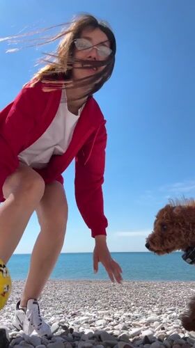 Woman plays with brown dog on Montenegro beach