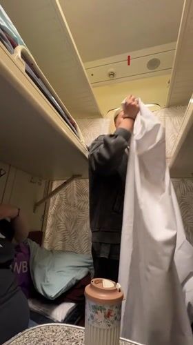 Woman makes bed in Russian train compartment