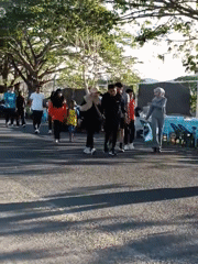 Pedestrians stroll tree-lined road in Lhokseumawe, Indonesia