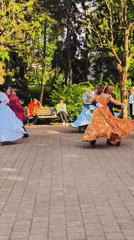 Costumed couples dance in formal attire at Riga park