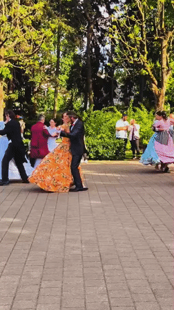 Costumed couples dance in formal attire at Riga park