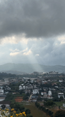 Hilltop city under dramatic overcast sky with breaking sunlight