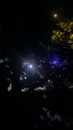Blue emergency lights flash outside during a late Warsaw night
