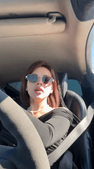 Woman drives through Нестюково wearing pearl necklace, sunglasses