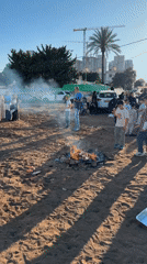 Children gather around bonfires on sandy lot in Netanya