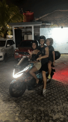 Three helmet-wearing riders share decorated scooter in Kuta