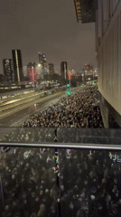 Large crowd gathers on London street near highway