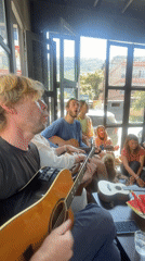 Dozen people play acoustic guitars indoors in Pokhara, Nepal