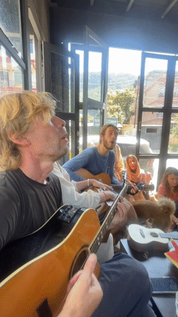 Dozen people play acoustic guitars indoors in Pokhara, Nepal