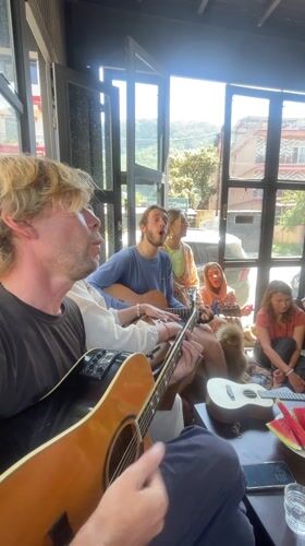 Dozen people play acoustic guitars indoors in Pokhara, Nepal