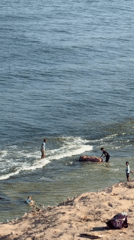 People at Deir al-Balah shore with cylindrical object in water