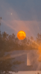 Massive orange moon rises low over Calgary's dusky sky