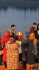 Group in traditional dress gathered near water in Jammu