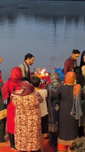 Group in traditional dress gathered near water in Jammu