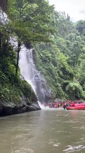 Life-jacketed group gathers at waterfall base in Payangan, Indonesia