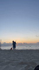 Beach worker rakes seaweed during sunrise in Playa del Carmen