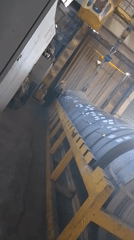 Worker stands atop metal coils in industrial warehouse