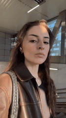 Woman in leather jacket observed near sunlit window in Moscow