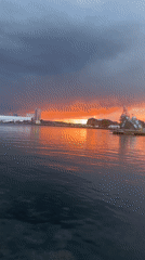 Storm clouds and fiery light over a city waterfront at dusk