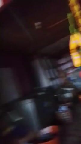 The video shows a cluttered interior space. A refrigerator, shelves with multiple objects, and various containers are visible. A figure appears briefly at the end. The lighting is poor, making details difficult to discern.