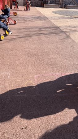 Children play outdoors with tricycles and hopscotch in France