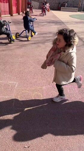 Children play outdoors with tricycles and hopscotch in France