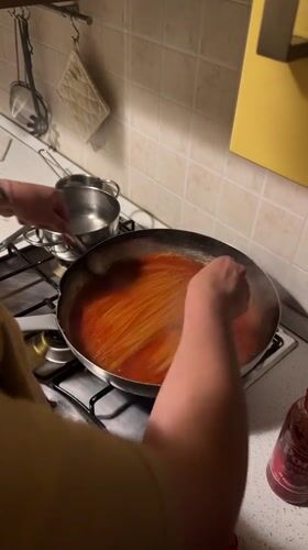 Person cooks spaghetti dinner in Milan kitchen