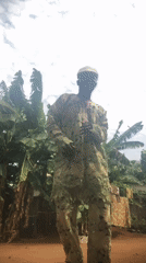 Man photographed in traditional green attire amid tropical foliage