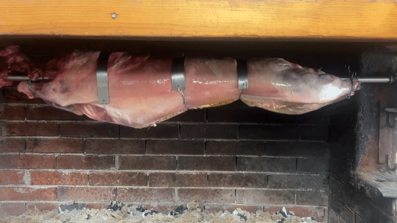 Lamb roasts on rotisserie in Bulgarian village fireplace