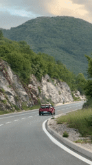 Red car travels mountain road near Vrela, Montenegro
