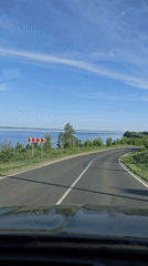 Car travels winding road near water in Khvalynsk, Russia