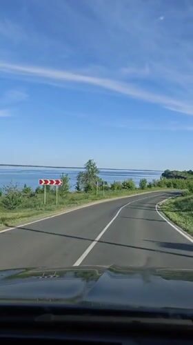 Car travels winding road near water in Khvalynsk, Russia