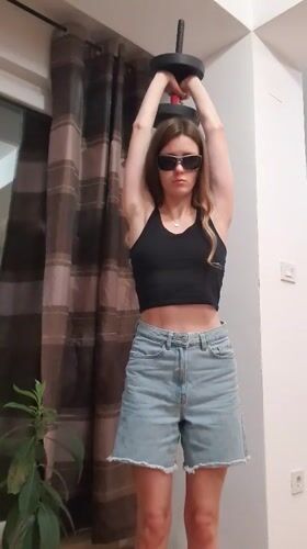 Woman performs indoor dumbbell workout in Bar, Montenegro