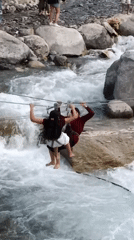 Tourists zip-line over rushing river in Old Manali