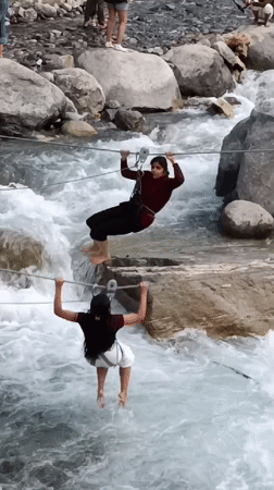 Tourists zip-line over rushing river in Old Manali
