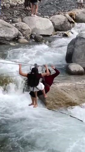 Tourists zip-line over rushing river in Old Manali