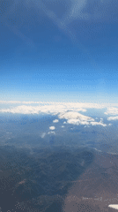 Aerial view captures snow-capped peaks above clouds in Sicily