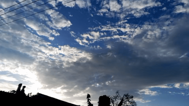 Witness captures partly cloudy sky with silhouetted landscape below