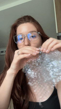 Woman pops bubble wrap in Thai kitchen, casual moment
