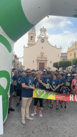Group of 60 people in blue shirts gather under archway in Spain