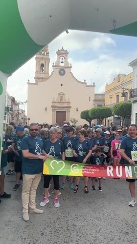 Group of 60 people in blue shirts gather under archway in Spain