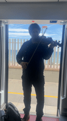 Violinist performs in train doorway in Spanish coastal town