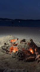Candlelit sandcastle glows on a Galician beach at night